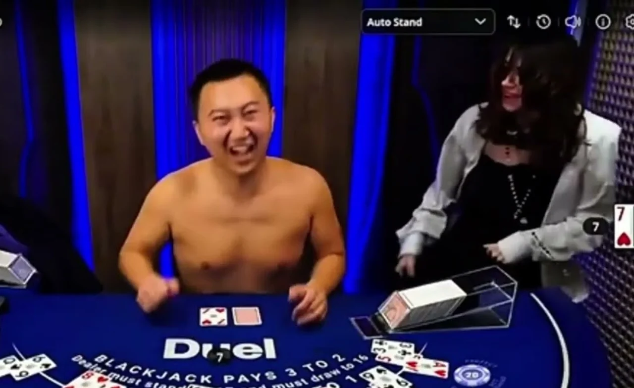 A shirtless dealer at the Duel blackjack table with a guest beside him and cards still on the felt